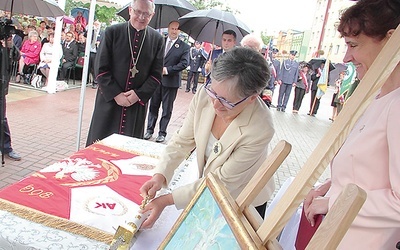 Danuta Ciesielska symbolicznie wbija gwóźdź w drzewce sztandaru szkoły.