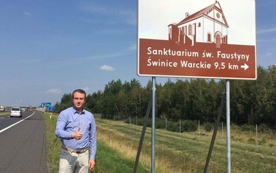 Senator Przemysław Błaszczyk przy znaku turystycznym na autostradzie A2