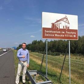 Senator Przemysław Błaszczyk przy znaku turystycznym na autostradzie A2