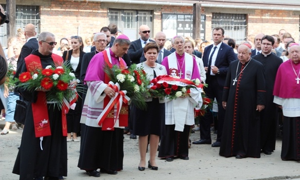 Bp Roman Pindel i premier Beata Szydło podczas złożenia kwiatów w miejscu placu apelowego, gdzie o. Kolbe zgłosił się na śmierć