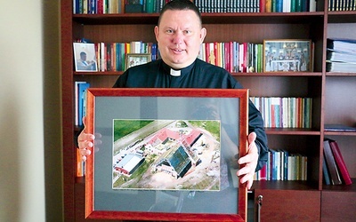 Ks. Dariusz Tkaczyk pokazuje zdjęcie z budowy kościoła.