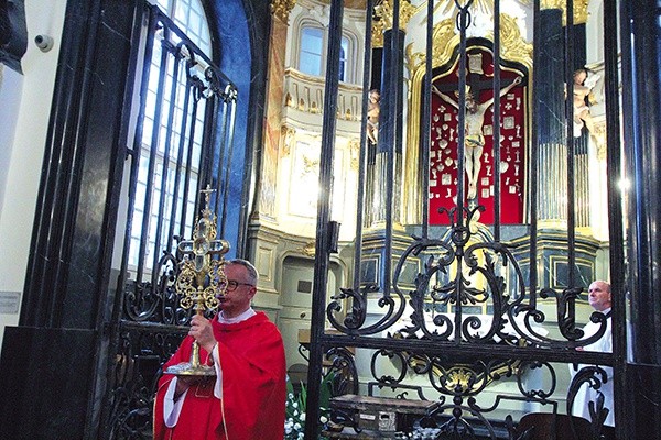 Proboszcz katedry błogosławi relikwiarzem z cząstką Drzewa Krzyża Świętego.