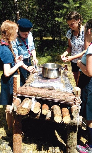 Gotowanie obiadu w obozowych warunkach. Harcerki rozpalają ogień na polowym piecu.