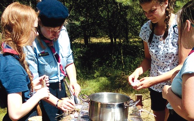 Gotowanie obiadu w obozowych warunkach. Harcerki rozpalają ogień na polowym piecu.