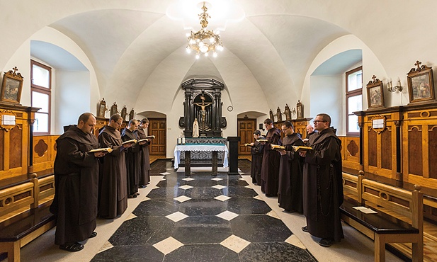 Karmelici odmawiają brewiarz w chórze  za ołtarzem.