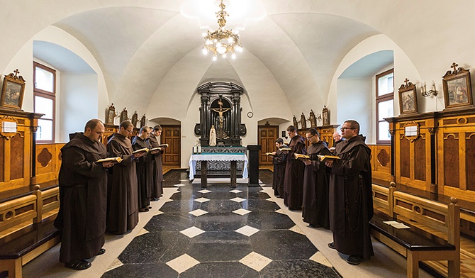 Karmelici odmawiają brewiarz w chórze  za ołtarzem.