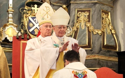 Abp Marek Jędraszewski nakłada dłonie na głowę bp. Wojciecha Osiala. Za nim bp Andrzej F. Dziuba