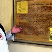 Ojciec Henryk Dereń pokazuje historyczną tablicę w wielisławskim sanktuarium.