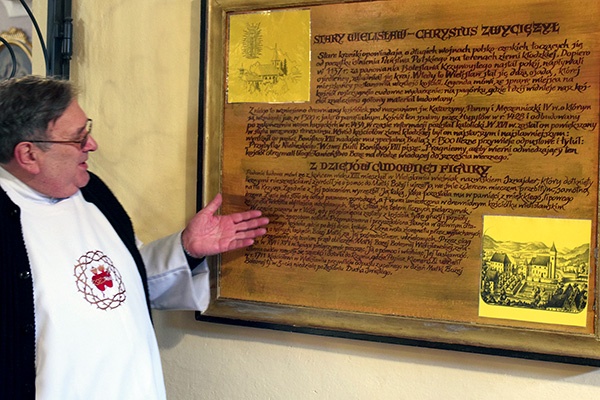 Ojciec Henryk Dereń pokazuje historyczną tablicę w wielisławskim sanktuarium.