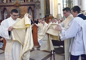 ▲	Zakładają stułę w poprzek ciała i wierzchnią szatę liturgiczną zwaną dalmatyką.