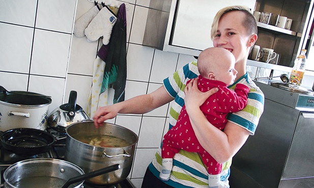 Dyżurująca w kuchni mama gotuje z synkiem na ramieniu. Trudne? Owszem, ale we własnym domu robiłaby dokładnie to samo.         
