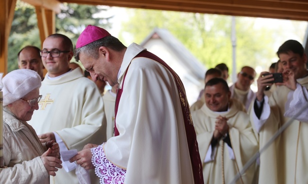 Najstarsza pątniczka Ludmiła Kołoczek wręcza bp. Pindlowi pakiet honorowego pielgrzyma z numerem 1