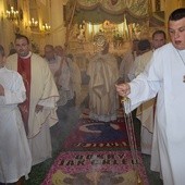 Bp Józef Zawitkowski niesie Najświętszy Sakrament po dywanie z kwiatów w kościele oo. pasjonistów w Rawie Mazowieckiej