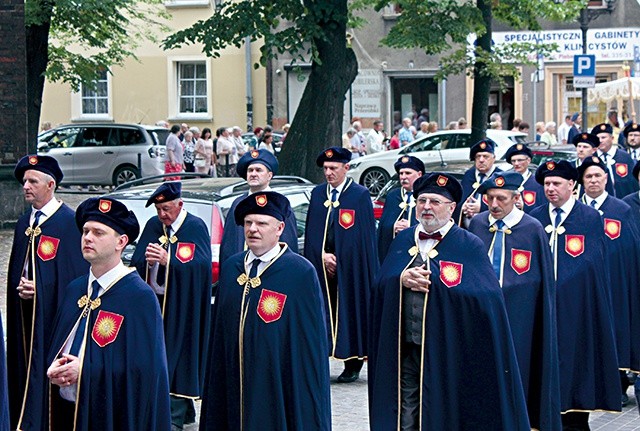 Mężczyźni w reprezentacyjnych strojach bractwa podczas procesji eucharystycznej.