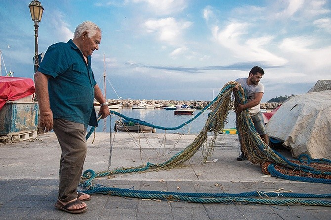 Stary Miguele razem z wnukiem naprawia sieć przed wypłynięciem na połów. Zawód rybaka przechodzi z ojca na syna.