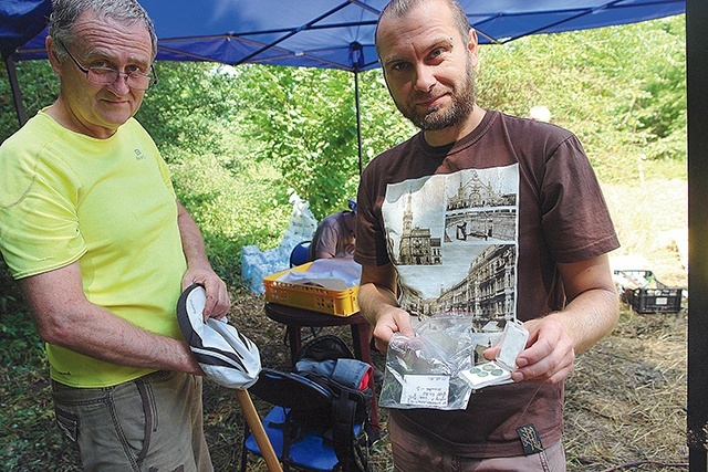 Andrzej Szelka i Radosław Zdaniewicz pokazują wydobyte z ziemi monety.