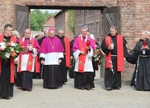 Biskupi i franciszkańscy współbracia św. Maksymiliana podchodzą do Ściany Śmierci obok bloku 11.