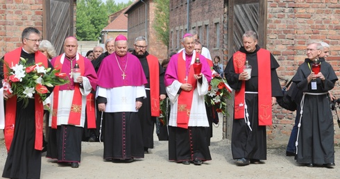 Biskupi i franciszkańscy współbracia św. Maksymiliana podchodzą do Ściany Śmierci obok bloku 11.