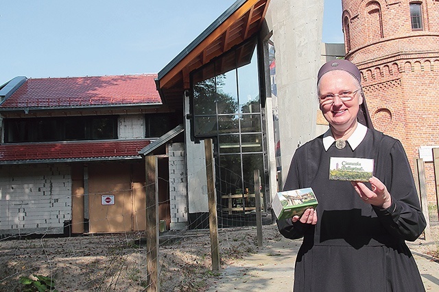 ▲	Na tle budowy Centrum s. Eligia prezentuje ciasteczka-cegiełki.