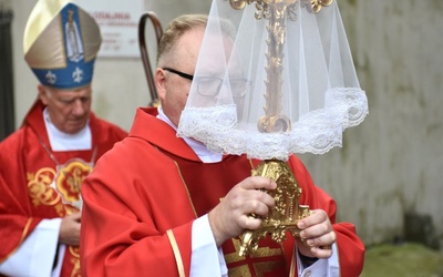 ks. Radosław Kisiel niosący relikwiarz z fragmentem krzyża świętego.