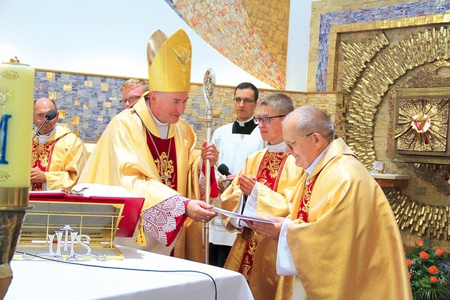 Biskup tarnowski Andrzej Jeż przekazuje ks. Edwardowi Litakowi świadectwo dedykacji kościoła.