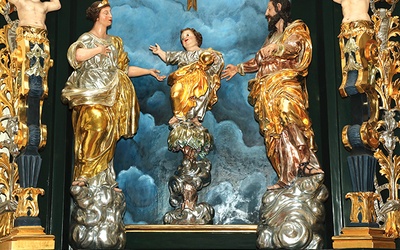 Artysta przedstawił Pana Jezusa stojącego dzielnie na palmie, w towarzystwie Maryi i św. Józefa.
