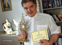 Ks. Zbigniew Chromy trzyma relikwie świętej z Umbrii i certyfikat potwierdzający ich autentyczność.