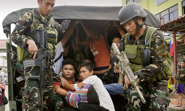 Żołnierze eskortują chrześcijan uwolnionych z muzułmańskiej niewoli w Marawi na wyspie Mindanao.