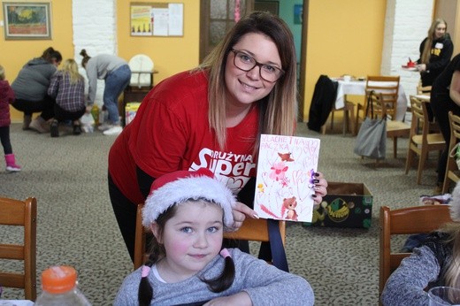 Marta Syposz, wolontariuszka z Ząbkowic Śląskich, trzyma laurkę narysowną przez dziewczynkę dla jednego z obdarowywanych dzieci.