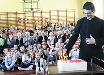 Ksiądz Damian Warzecha zapala świeczki  na jubileuszowym torcie.