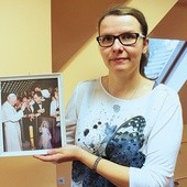▲	Aneta Korzuśnik z pamiątkowym zdjęciem. Przedstawia ono Jana Pawła II błogosławiącego obraz Jezusa Miłosiernego, który znajduje się w kaplicy placówki. 