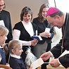 ▲	Biskup Jeż dzieli się opłatkiem z dziećmi ze szkoły katolickiej.