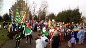 Uczestnicy orszaku w barwnych strojach i koronach przed kościołem parafialnym