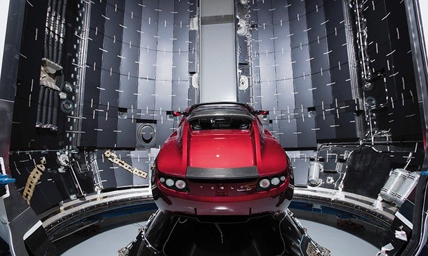 Ten sportowy samochód Tesla Roadster w kolorze wiśniowym leci w kierunku Marsa  na pokładzie rakiety Falcon Heavy.