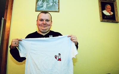 ▲	Ks. Sebastian Antosik prezentuje koszulkę.