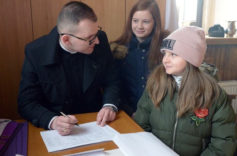 Na oazę Zuzannę Wiktorowicz (w środku) i Julię Kowalczyk zapisuje ks. Łukasz Białas