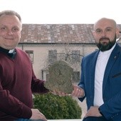 Ks. Robert Kowalski (z lewej) i ks. Damian Drabikowski, wicedyrektor radomskiej Caritas, pokazują znaleziony podczas remontu kaplicy stary żeliwny odlew głowy Chrystusa. W tle dawna kaplica, obecnie magazyn radomskiej organizacji charytatywnej