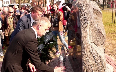 Krzysztof Jan Kaliński z zapalonym zniczem przy głazie w Łowiczu.