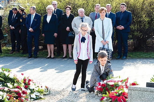 Uczniowie zabrzańskich szkół składają kwiaty przy tablicach upamiętniających ofiary zbrodni katyńskiej i katastrofy smoleńskiej. W tle przedstawiciele władz miasta.