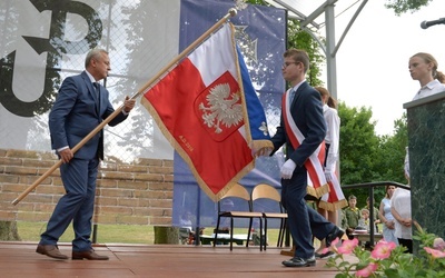 Poświęcony sztandar przekazuje uczniom Jan Słuszniak, dyrektor placówki w Baryczy