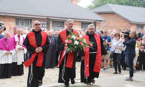 Franciszkanie przed tablicą upamiętniającą wystąpienie o. Kolbego podczas apelu