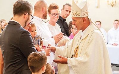 ▲	Biskup Andrzej wręcza świece rodzinom, które wstępują do Domowego Kościoła.