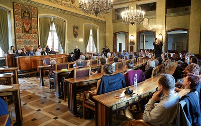 Poeci czytają Herberta w sali magistratu Krakowa.