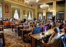 Poeci czytają Herberta w sali magistratu Krakowa.