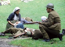 ◄	Sanitariuszka niosąca pomoc polskim żołnierzom na polu walki z Sowietami. Rekonstrukcja historyczna.