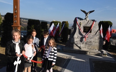 Dzieci z patriotycznym różańcem przed obeliskiem