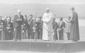 Warszawa, 2 czerwca 1979 r. Przemówienie powitalne przewodniczącego Rady Państwa PRL Henryka Jabłońskiego. Na podium widoczni również: papież Jan Paweł II, prymas Polski, kard. Stefan Wyszyński. W 1. rzędzie za podium widoczni m.in. prefekt Domu Papieskiego, bp Jacques Martin (1. na prawo od H. Jabłońskiego), abp Eduardo Martinez Somalo (3. na prawo od H. Jabłońskiego), sekretarz papieża, ks. Stanisław Dziwisz (1. na prawo od Jana Pawła II)