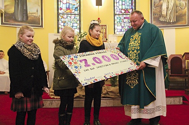 Dzieci z parafii w Żórawinie przekazują symboliczny, przygotowany przez siebie czek ks. Waldemarowi Cisło.