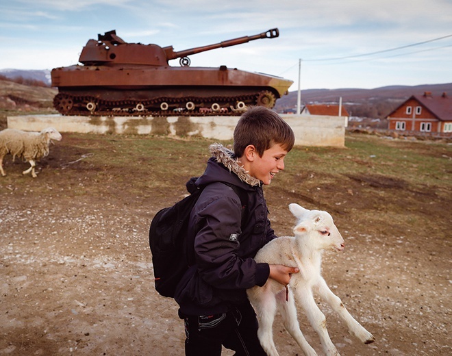 Albański chłopiec niesie baranka podczas spaceru w pobliżu zniszczonego serbskiego czołgu.
13.03.2019 Fusztica, Kosowo