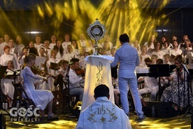 Najświętszy Sakrament otoczony gronem muzyków w blasku reflektorów.